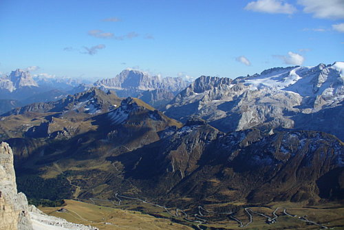   Pohľad zo Sass Pordoi na legendárne masívy (zľava) Monte Pelmo (3168m), popod ktorý vedie cesto Forcella Staulanza, ďalej Monte Civetta (3218m) a Marmolada (3342m), v údolí serpentíny východnej rampy Pordoijochu (Passo Pordoi)